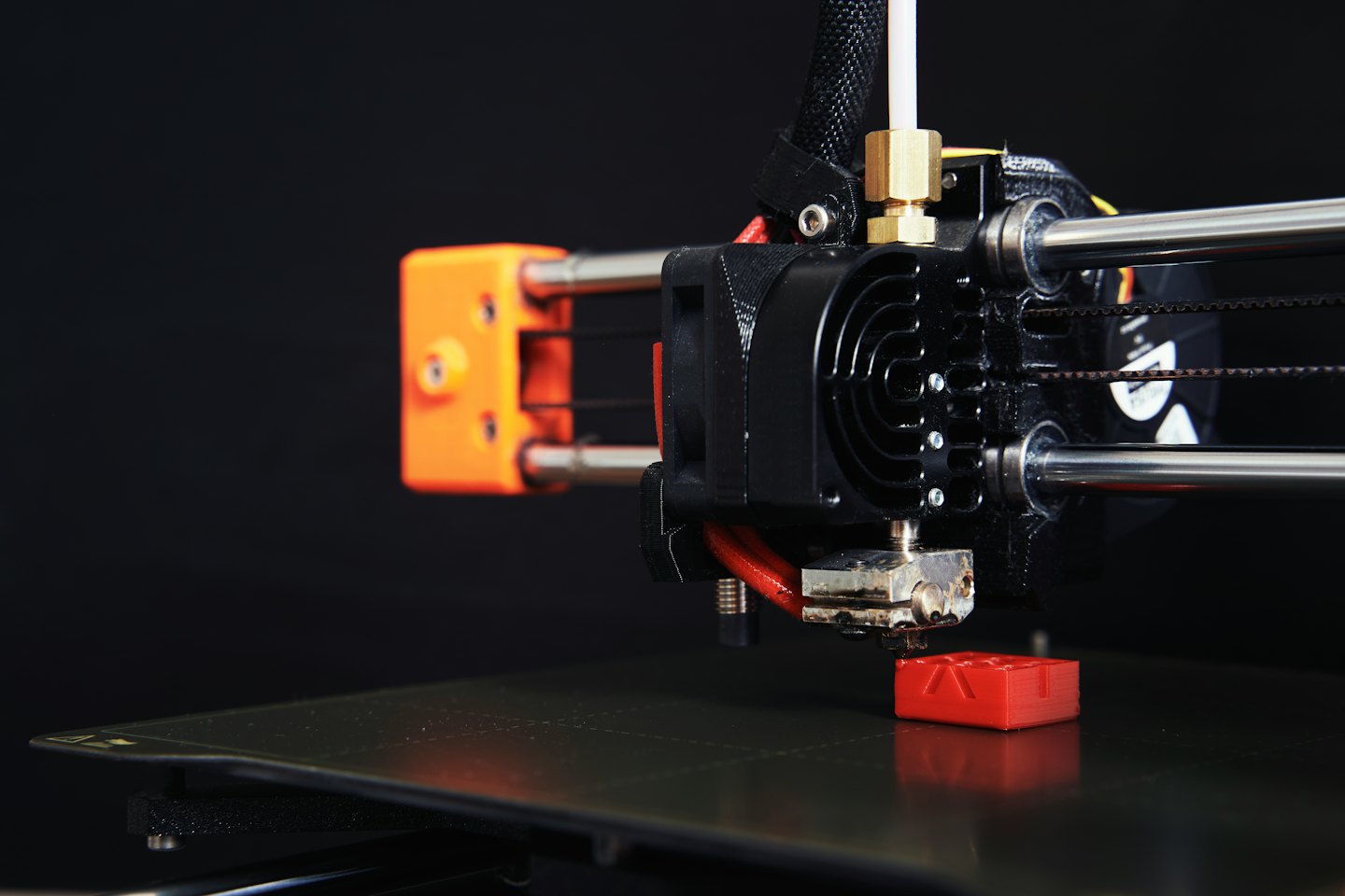 3D printer building a small red object.