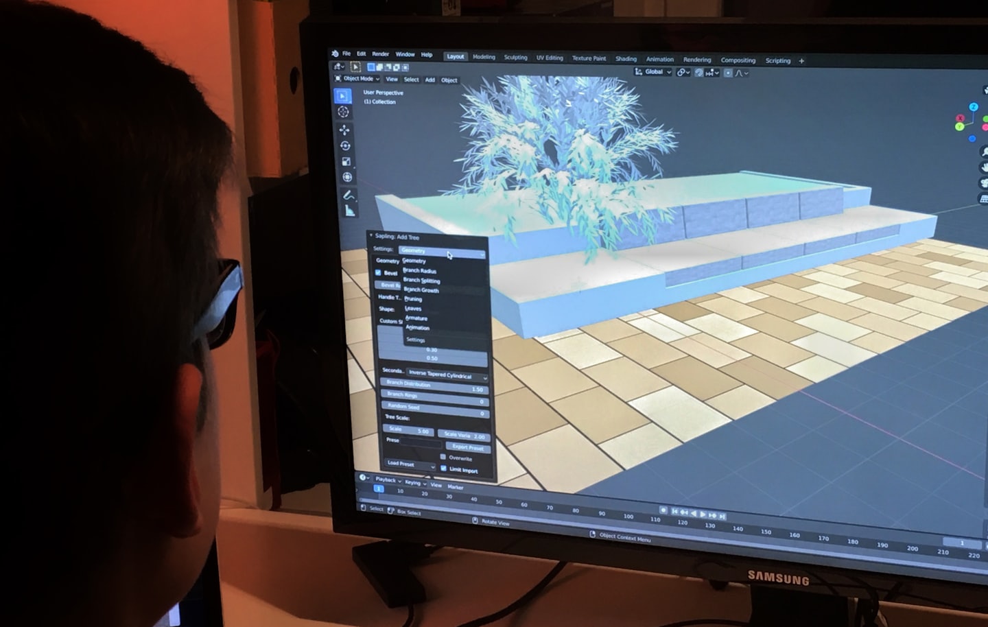 Designer works on 3D modeling software displaying a digital tree.