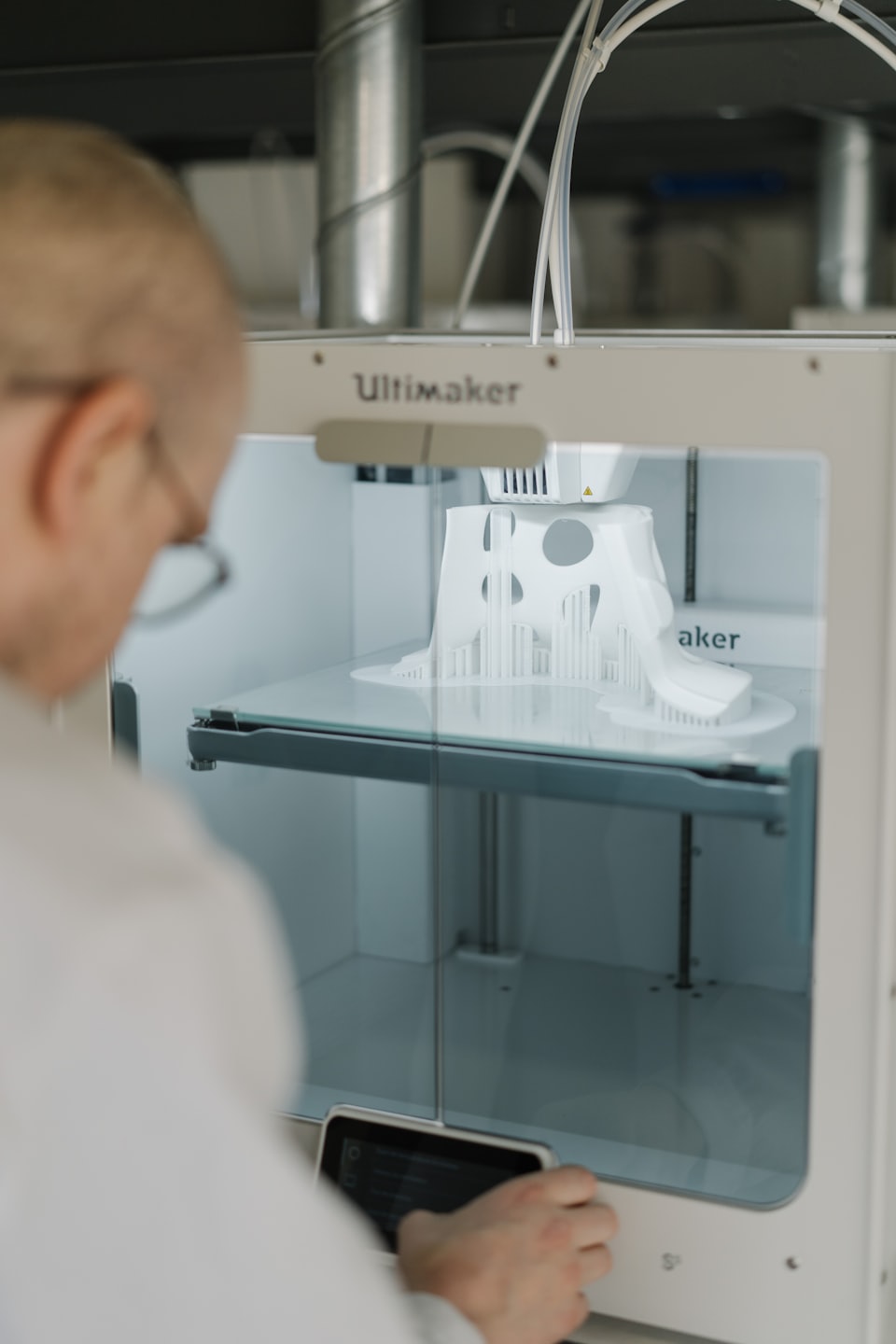 Scientist operates a 3D printer creating a white object.